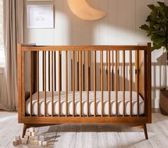 a wooden crib in the corner of a room with a plant on the floor