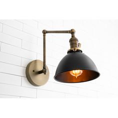 a black and gold wall light next to a white brick wall in an industrial style