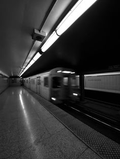 a train traveling through a subway station next to a loading platform with no people on it