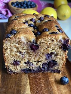 a loaf of blueberry bread sitting on top of a wooden cutting board