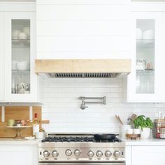 a stove top oven sitting inside of a kitchen next to white cabinets and counter tops