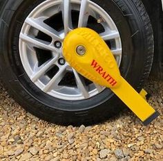 a wheel with a yellow wrench attached to it sitting on the ground next to a car