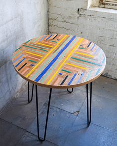 a wooden table with multicolored lines painted on it and black hairpin legs