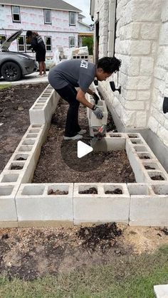 two men are working in the yard with cement blocks and plants growing out of them