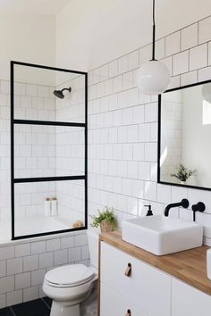 a white bathroom with black and white tiles on the walls