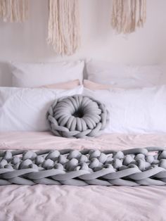 a bed with white sheets and pillows on top of it next to two decorative objects