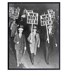 three men walking down the street holding signs that say we want beer and one man is wearing a suit