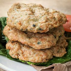 three crab cakes stacked on top of each other with lettuce and tomato in the background