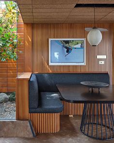 a table and chairs in a room with wood paneling on the walls, along with an art piece hanging above it