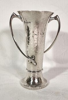 a silver vase sitting on top of a white table