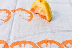 an orange cut in half sitting on top of a white table cloth next to a piece of fruit