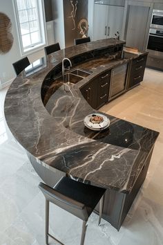 a large kitchen with marble counter tops and an island in the middle, along with two black chairs