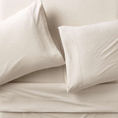 two white pillows sitting next to each other on top of a bed covered in sheets