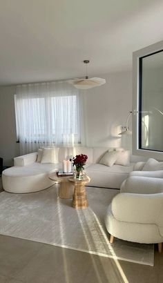 a living room with white furniture and large windows