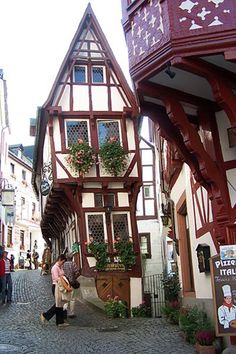 two people walking down a cobblestone street in an old european town with half - timbered buildings