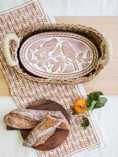 bread and oranges on a table with a decorative tray in the middle, next to it