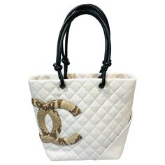 - Chanel white lambskin quilted tote bag with embossed snakeskin "CC” logo. - Orange "CC” satin lining with zip closure. - Exterior slip pocket. - Two interior zip pockets - Length: 20cm. - Height: 24cm. - Width: 11cm. - Handle Drop: 21cm. Luxury Quilted Bags For Daily Use, White Quilted Top Handle Bag, Luxury White Quilted Shoulder Bag, Luxury White Soft Leather Bag, Luxury Quilted Cream Shoulder Bag, White Quilted Tote Shoulder Bag, Chanel Top Handle Bag, God Energy, Chanel Top Handle