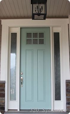 a blue front door with two sidelights and a lantern on the top of it