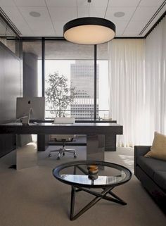 an office with a glass table and black couch