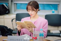 a woman sitting at a table reading a book