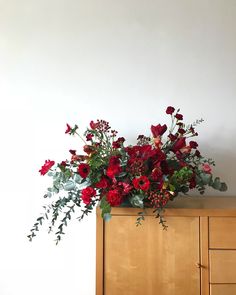 a wooden cabinet with flowers and greenery on top