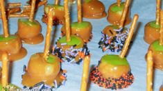 caramel apples with sprinkles and candies are arranged on a table