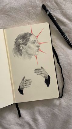 an open notebook with a drawing of a woman's face and hands on it