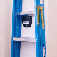 a blue ladder is next to a white wall with a black and silver object on it