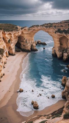 the beach is next to an arch shaped rock formation