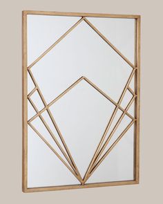 a gold framed mirror with geometric shapes on the front and back side, against a gray background