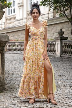 a woman in a yellow floral dress posing for the camera with her legs slited