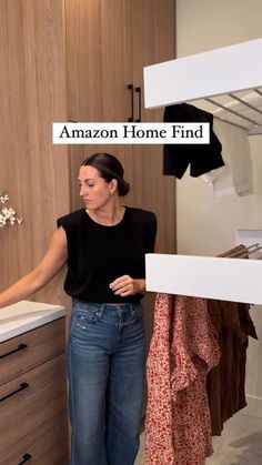 a woman standing in front of a closet with clothes hanging on the rack and an amazon home find sign above her