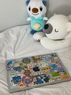 two stuffed animals sitting next to each other on a bed