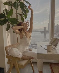 a woman sitting at a desk with her arms up in the air