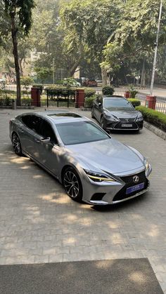 two cars parked on the side of a road next to each other in front of trees