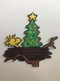 a cross stitch christmas tree on top of a wooden table next to a white wall