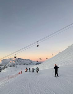 skiers and snowboarders at the bottom of a ski slope with a lift in the background