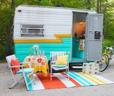 a vintage camper is parked next to a picnic table with chairs and a bike