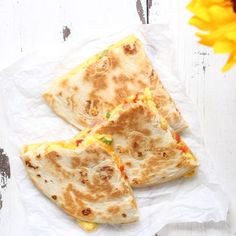 three quesadillas sitting on top of a piece of paper next to a sunflower