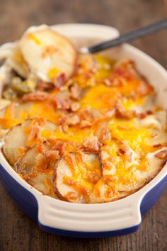 a casserole dish with potatoes and bacon in it on a wooden table, ready to be eaten