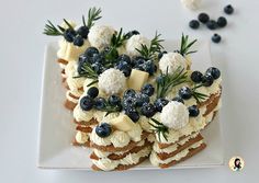 a white plate topped with crackers covered in cheese and blueberries next to sprigs of rosemary