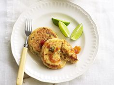 two fritters on a plate with a fork and lime wedges next to them