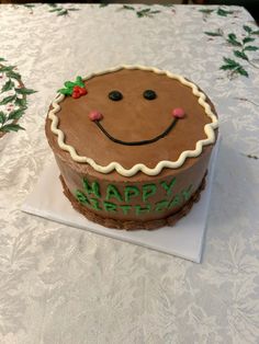 a decorated cake sitting on top of a white tablecloth covered table with christmas decorations