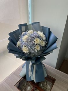 a bouquet of white and blue flowers sitting on top of a table