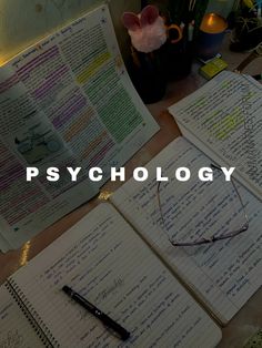 an open notebook sitting on top of a wooden table next to a pen and glasses