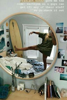 a woman standing in front of a mirror holding a surfboard