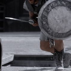 a man in shorts and sneakers holding a large metal object with one foot on the ground