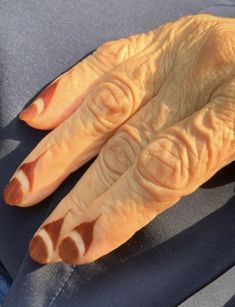 an older woman's hand with orange and white designs on it