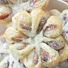 several pastries in a white bowl with powdered sugar on top