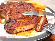 there is a piece of meat on the plate with a fork and knife in it